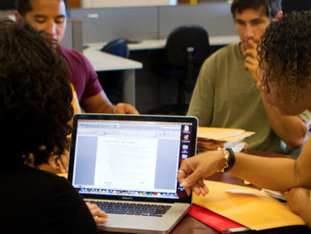 Students gathered around table with computers