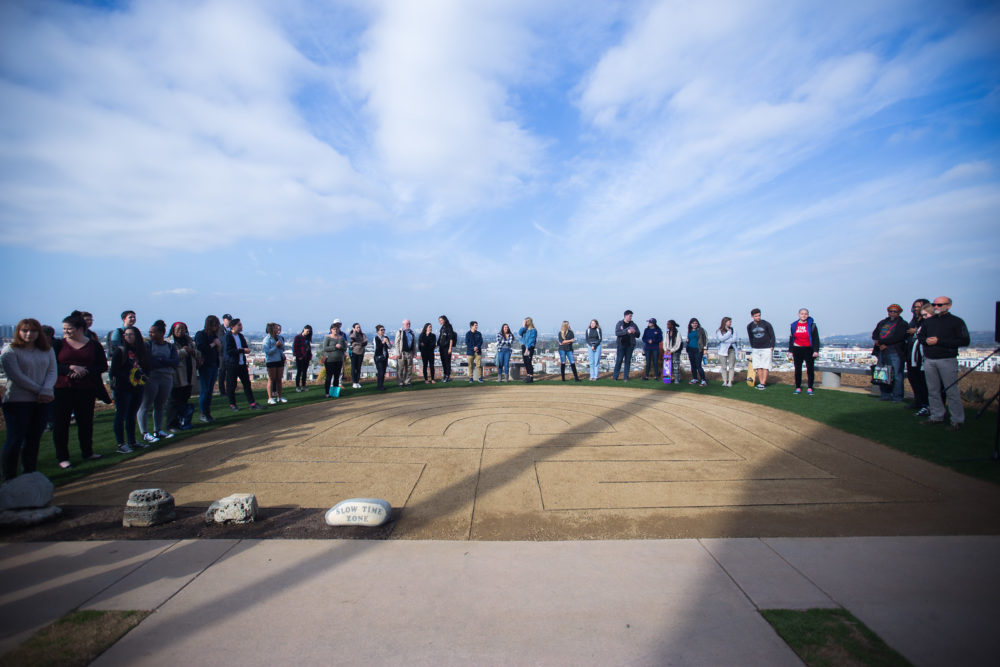 Students surrounding outdoor labyrinth on bluff