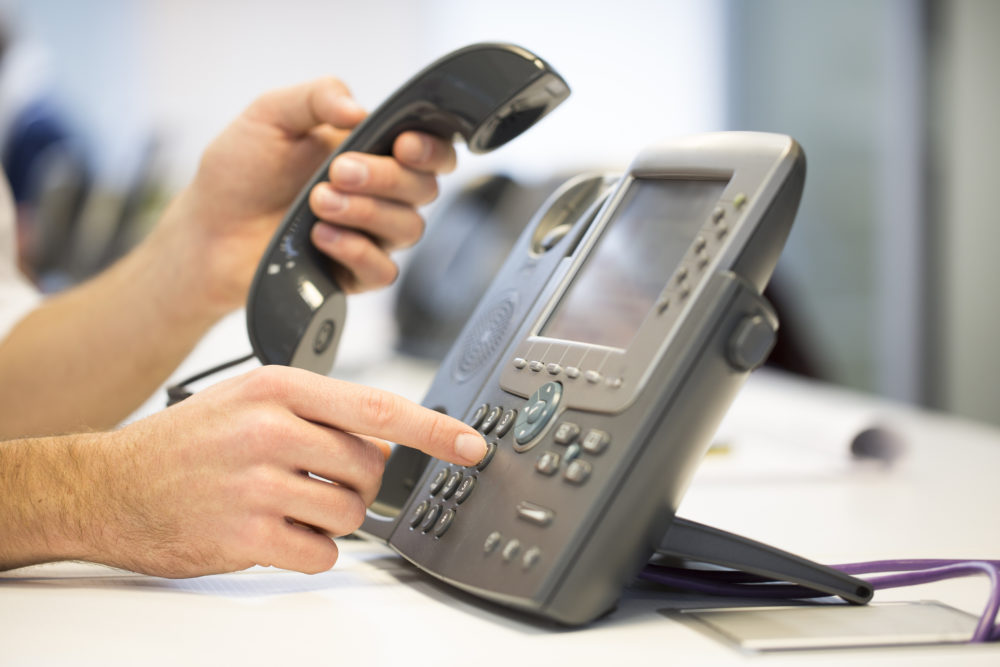 Man hand is dialing a phone number, office Background