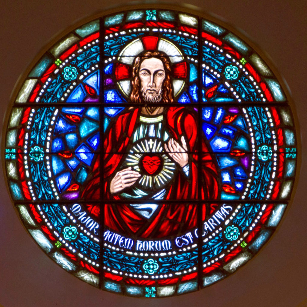 The Rose Window at the back of Sacred Heart Chapel depicting an image of the Sacred Heart of Jesus with the Latin inscription Love is the most important