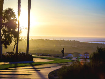 student walks on LMU campus at sunset, with ocean on horizon