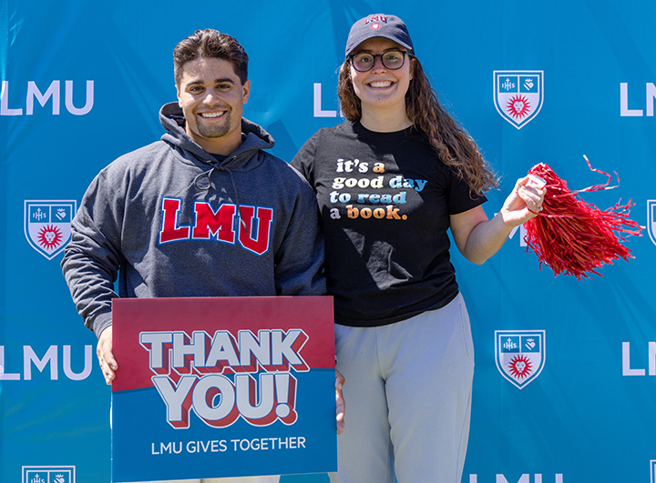 Two excited students holding a sign saying Thank You