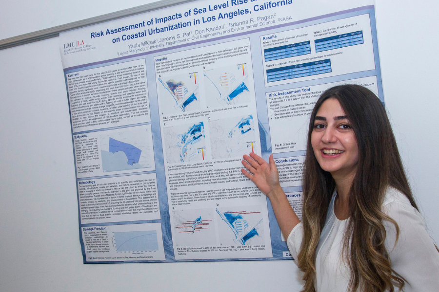 A student smiles standing next to her project