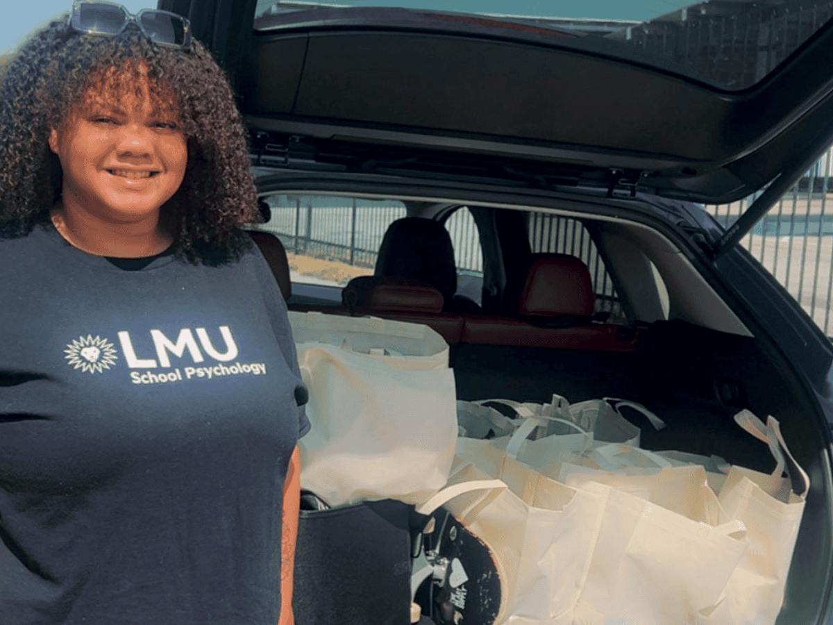 woman standing next to a car with an open trunk full of grocery bags