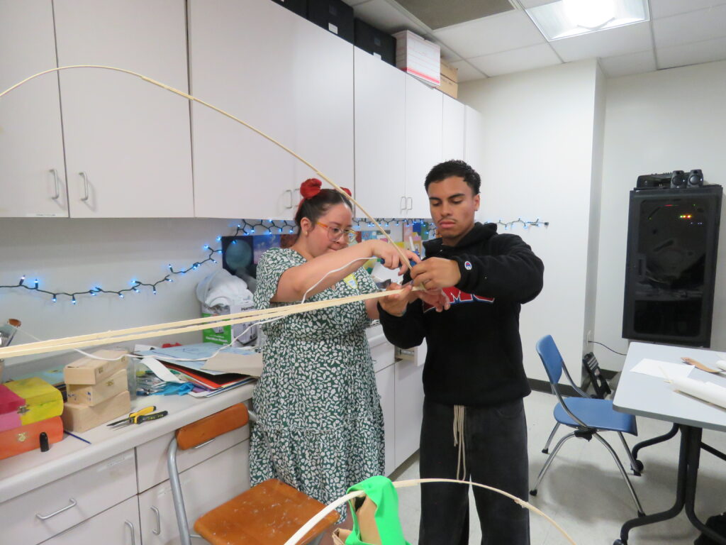 Mikey Sanchez '25 helps a student build a bridge.