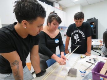 Three students work on an art project, building bridges.