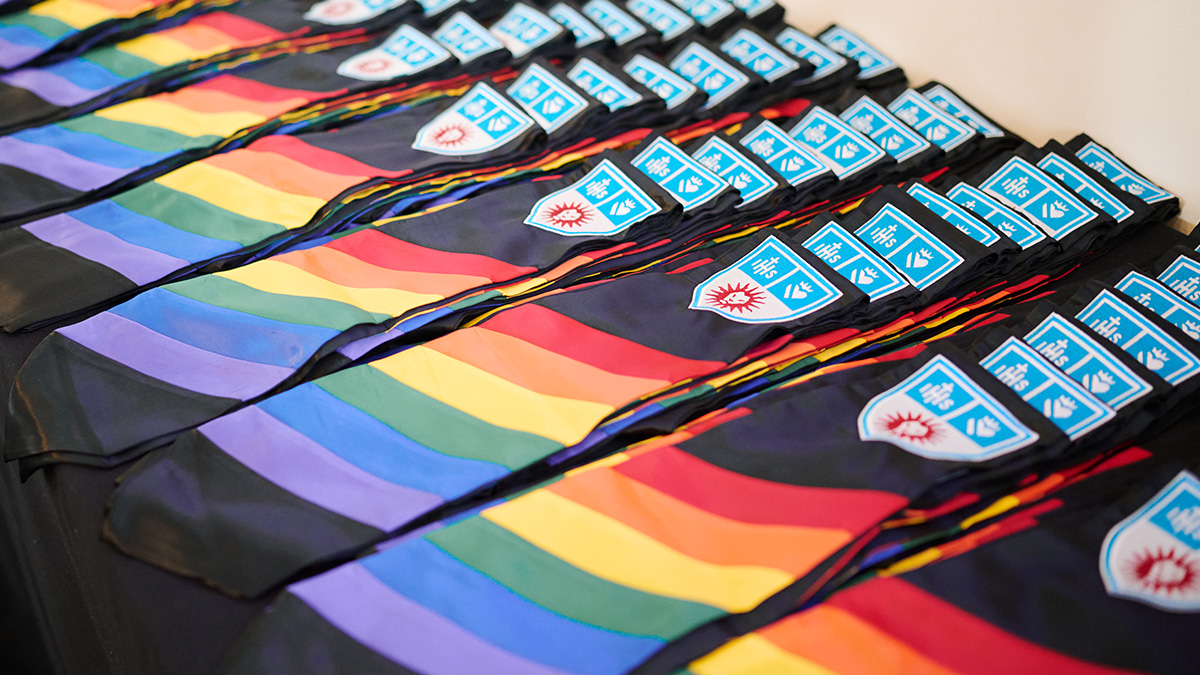 Rainbow flags on black stoles with the LMU logo.