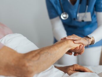 Close-up of caregiver holding senior client hand.