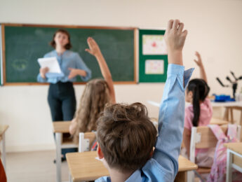 Students raising their hands in a classroom