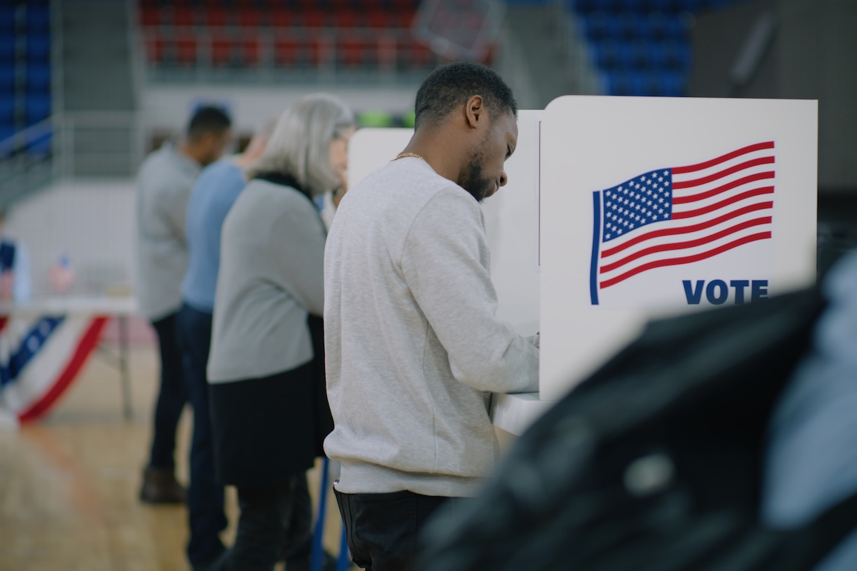 Man stands at a voting booth filling out ballot