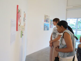 Two students look at artwork on an exhibit wall
