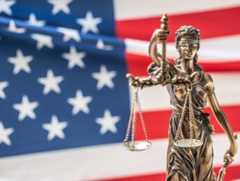 The statue of justice, goddess of justice in front of american flag.