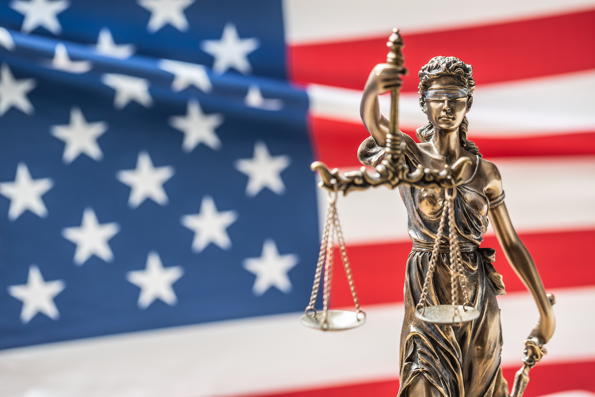 The statue of justice, goddess of justice in front of american flag.