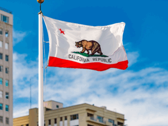 California Flag on flagpole in front of a building and blue sky