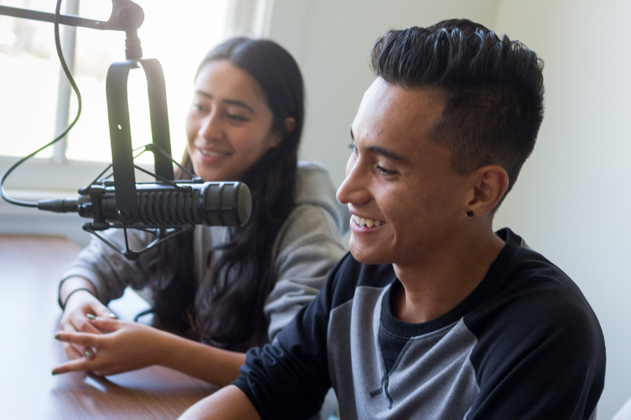 Students speak in microphone in a podcast studio