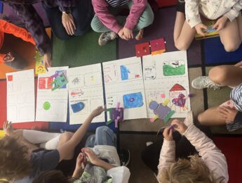 Overhead shot of young students gathered around art supplies and paper