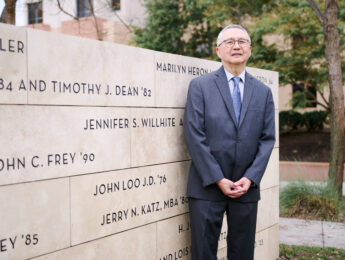 John Loo standing in front of donor wall