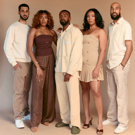 The co-founders of WalkGood LA pose against a tan backdrop in tan, white, and brown clothing.