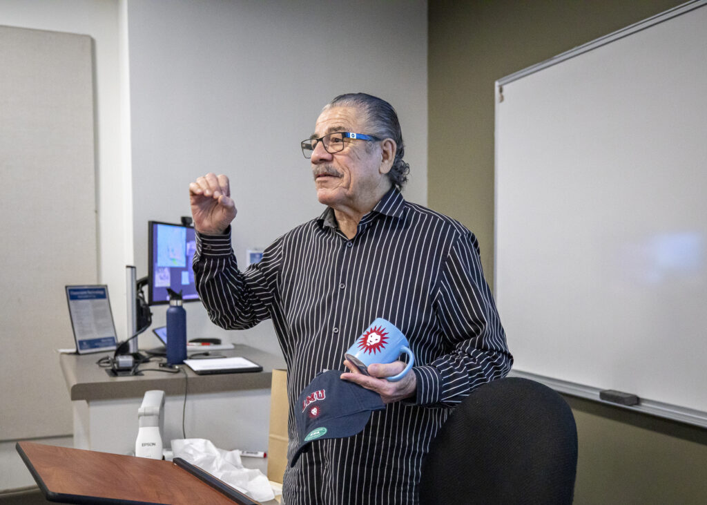 Jacob Stitch Duran speaking in classroom holding LMU gear.