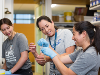 LMU biology professor Christina Vasquez shows two students how to work with mussels in the lab