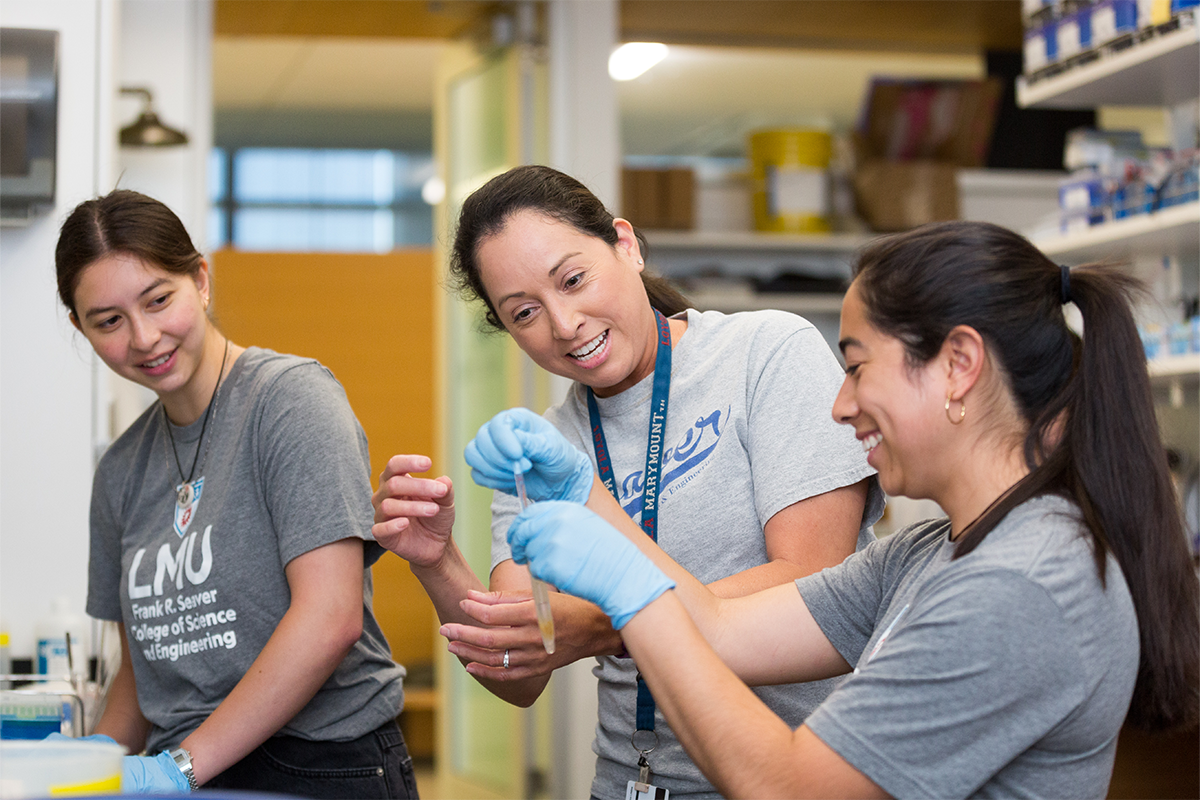 LMU biology professor Christina Vasquez shows two students how to work with mussels in the lab