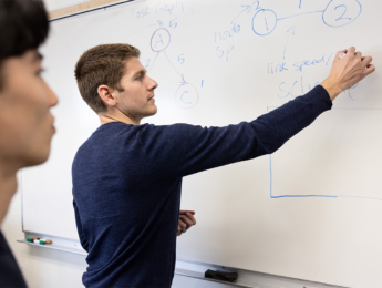 LMU computer science professor Jared Coleman writing on the white board.