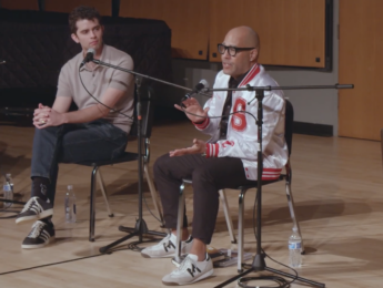 Two men speak on stage