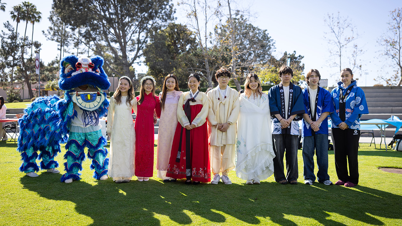 Students and staff stand outside dressed in traditional attire to celebrate Lunar New Year.