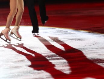 Winter Sports Concept. Figure Skating Elements. Low Section Of Unknown Ice Dancing Couple With Illuminating Ice Reflection, Copy Space, Neon Lighting