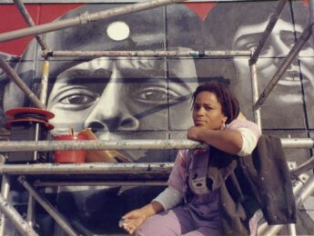 Olabisi sitting on scaffolding while painting her mural