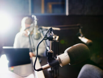 Shot of a microphone in a recording studio with the presenter blurred in the background