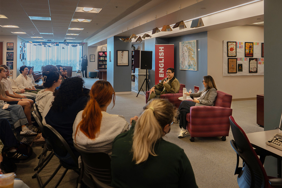 Randall Park seated in chair facing room full of students in the LMU English Department village.