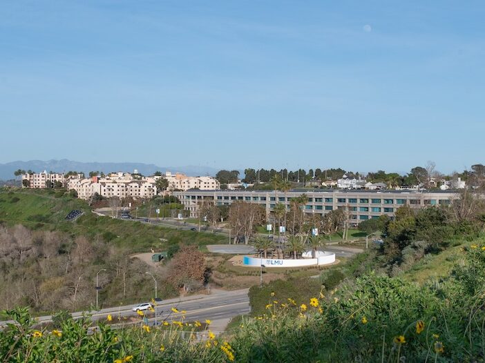 LMU campus from a distance with LMU signage and wildflowers.