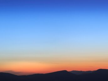 Photo of blue and orange sky over dark mountains