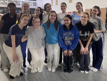 Twelve girls pose together in a dance studio