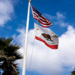 US flag and California state flag on a flag pole.
