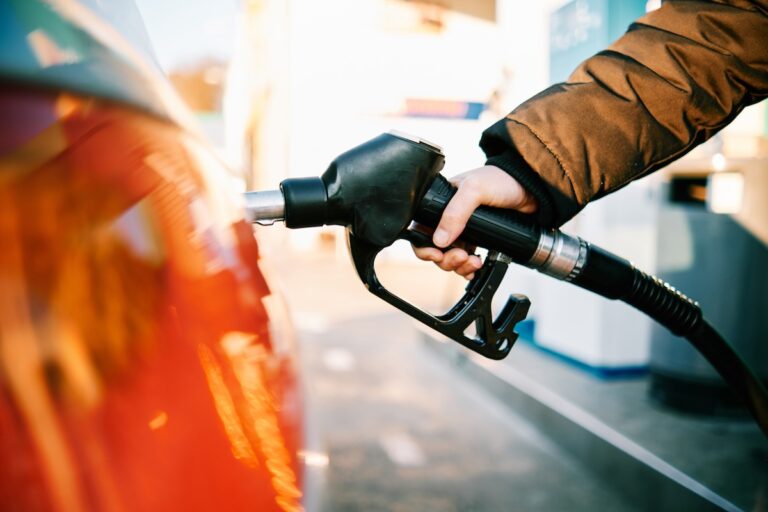 close-up of a hand in a gas pump fueling a car