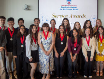 Students gather wearing red ribbon and gold medals or holding clear star awards during the annual CSA Service Awards.