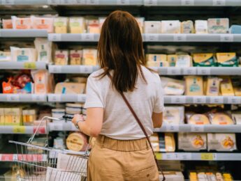 Woman choosing dairy products from the refrigerator in supermarket.