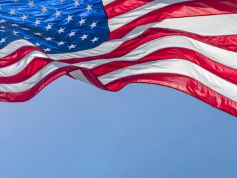 Low angle view of American flag waving in wind against clear sky