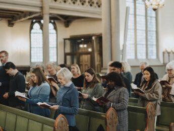 People in pews reading hymnbook during mass at church