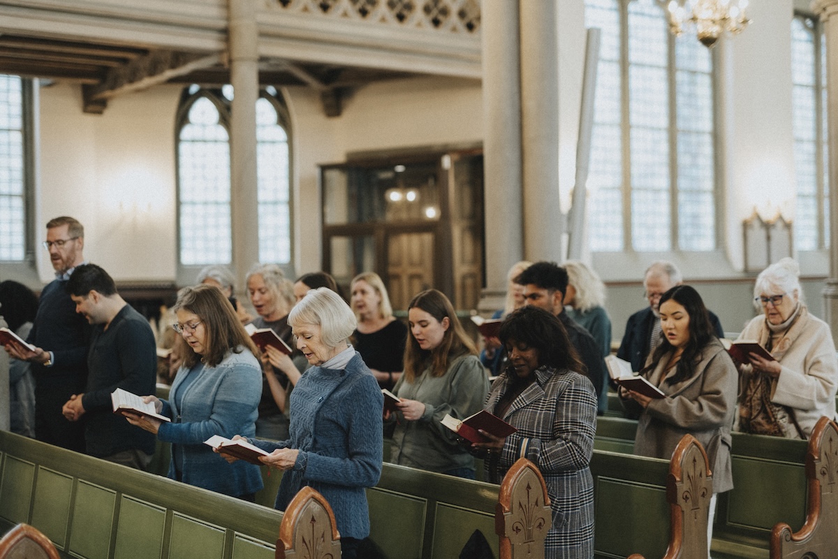People in pews reading hymnbook during mass at church