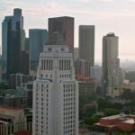 Aerial shot of Los Angeles City Hall in Downtown Los Angeles with financial district skyscrapers in background at sunset.