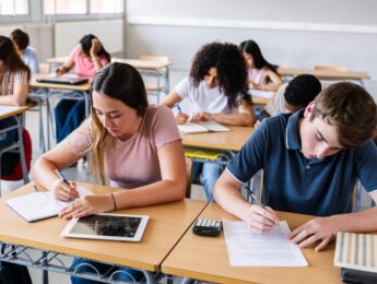 Young group of students writing while learning during a class at high school.