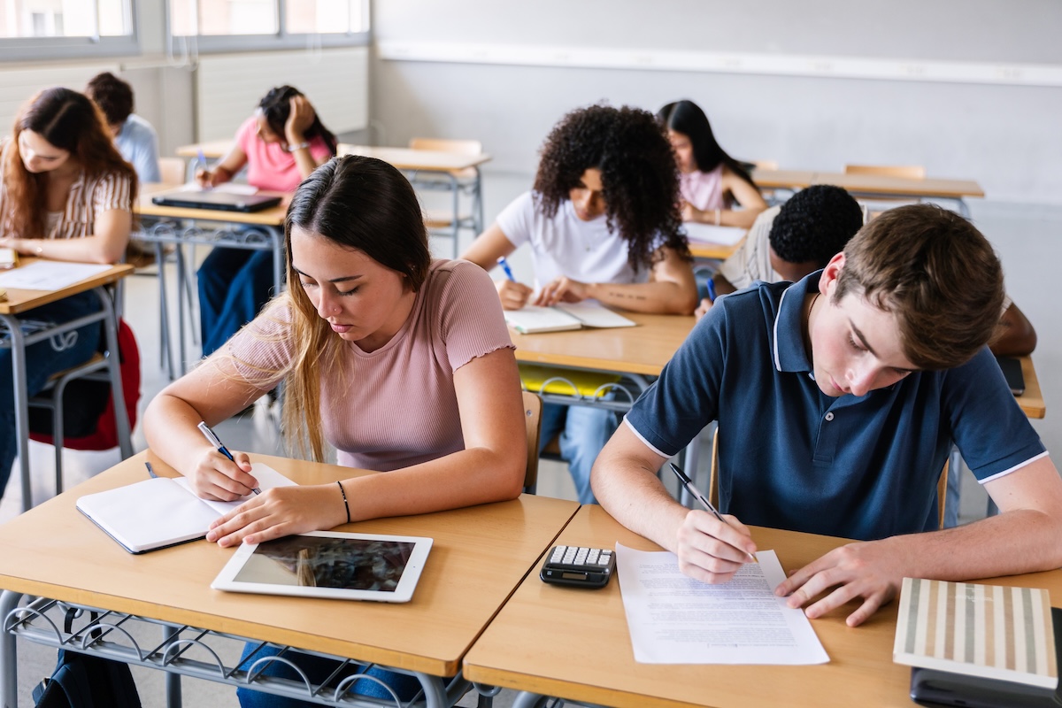Young group of students writing while learning during a class at high school.
