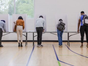 Group of voters use privacy partitions to fill out their ballots in the election event.