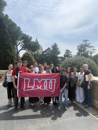 Students holding the LMU flag in front of St. Peter's Basilica in Vatican City