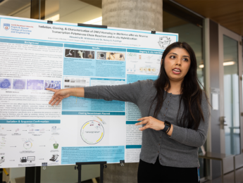 Female Seaver student pointing at their poster at 2026 Summer Poster presentation for SOAR Anniversary