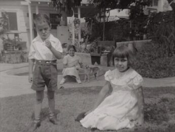 Siblings Lawrence “Buddy” (left) and Carol (right) are in the foreground, while their neighbor Lolita (middle) sits with the family dog, Blondie, on a raised cement flower planter in their lawn under an avocado tree. Courtesy Carol Jacques, Chavez Ravine: An Unfinished Story archival collection