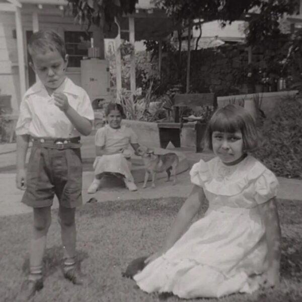 Siblings Lawrence “Buddy” (left) and Carol (right) are in the foreground, while their neighbor Lolita (middle) sits with the family dog, Blondie, on a raised cement flower planter in their lawn under an avocado tree. Courtesy Carol Jacques, Chavez Ravine: An Unfinished Story archival collection